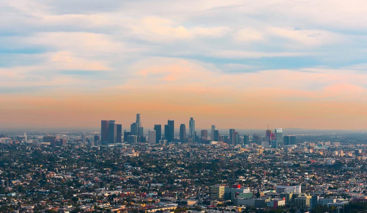 cityscape of downtown los angeles and outlying areas with orange clouds in sky