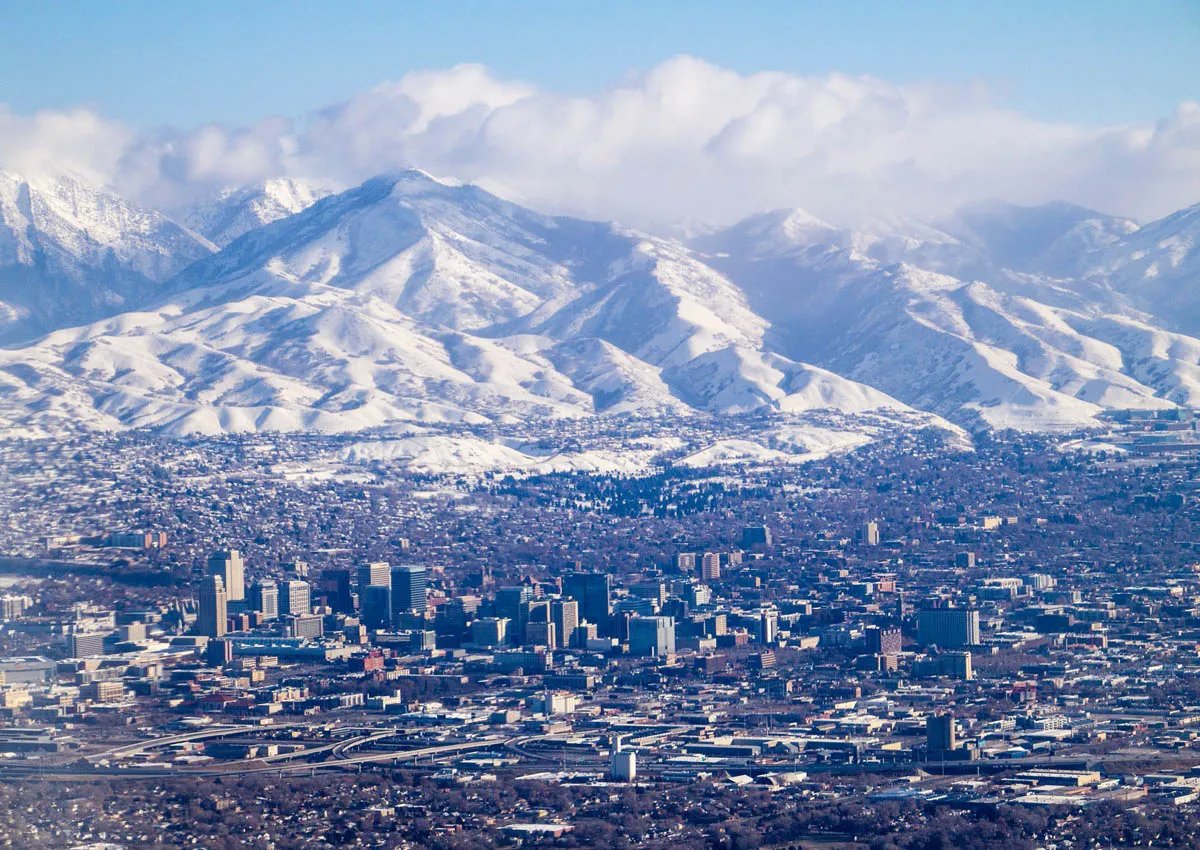 cityscape of salt lake city with snowy mountain caps and clouds in the background