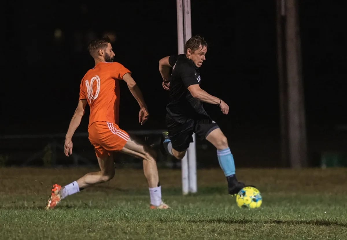 two adult male soccer players attacking ball
