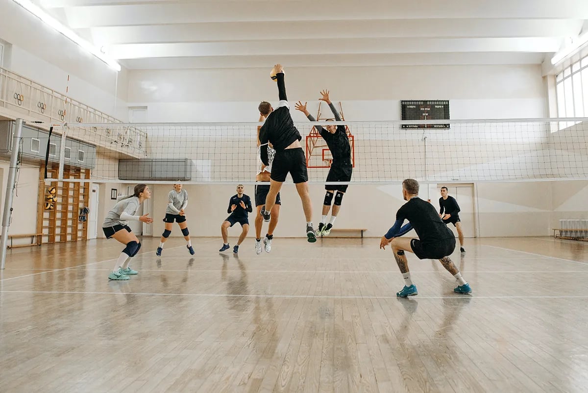 indoor volleyball game with two men jumping at net
