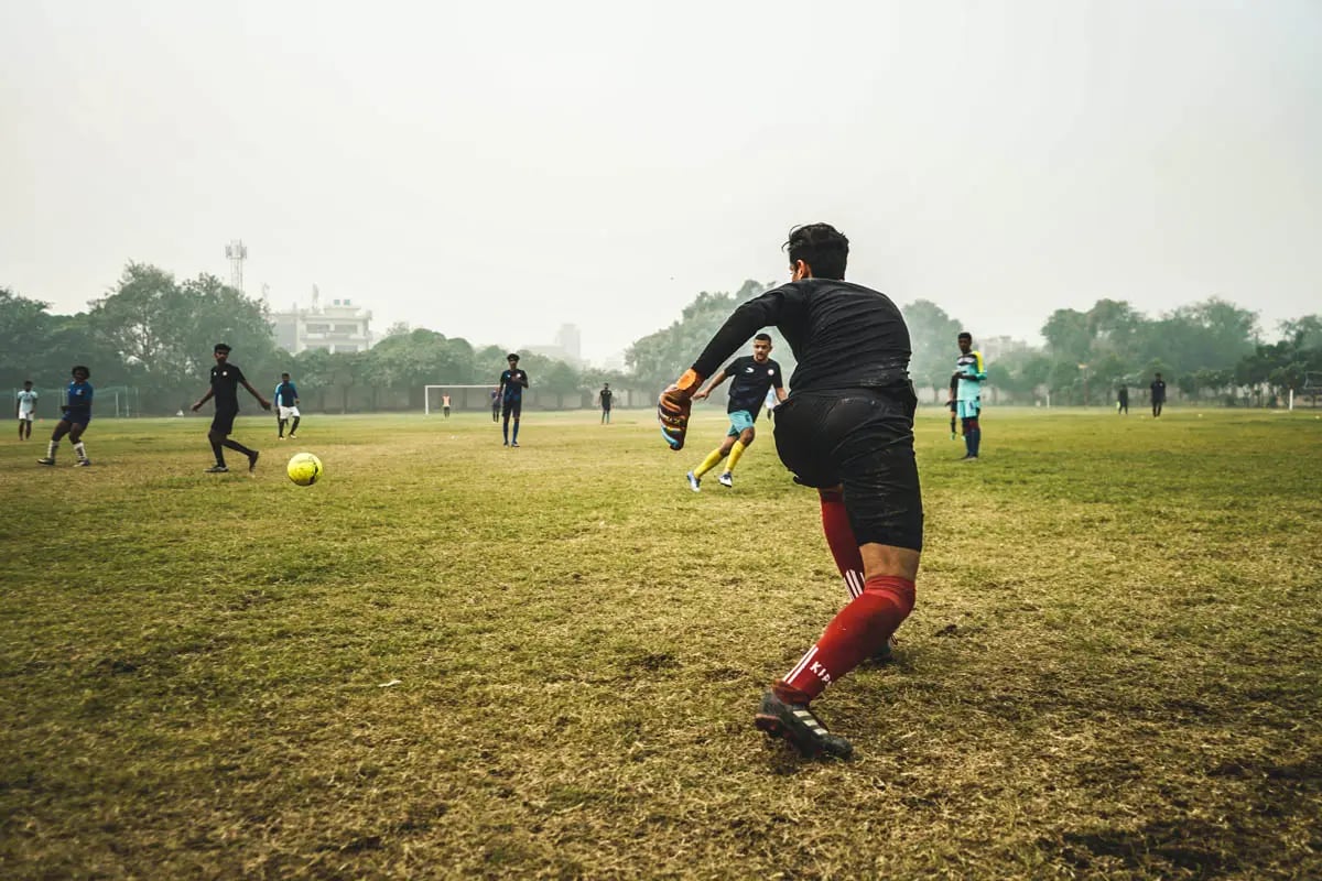 male adult soccer players soccer in a park in cloudy hazy weather