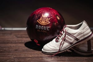 closeup of red bowling ball and white bowling shoe
