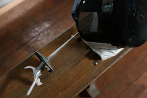 fencing mask and foil on bench