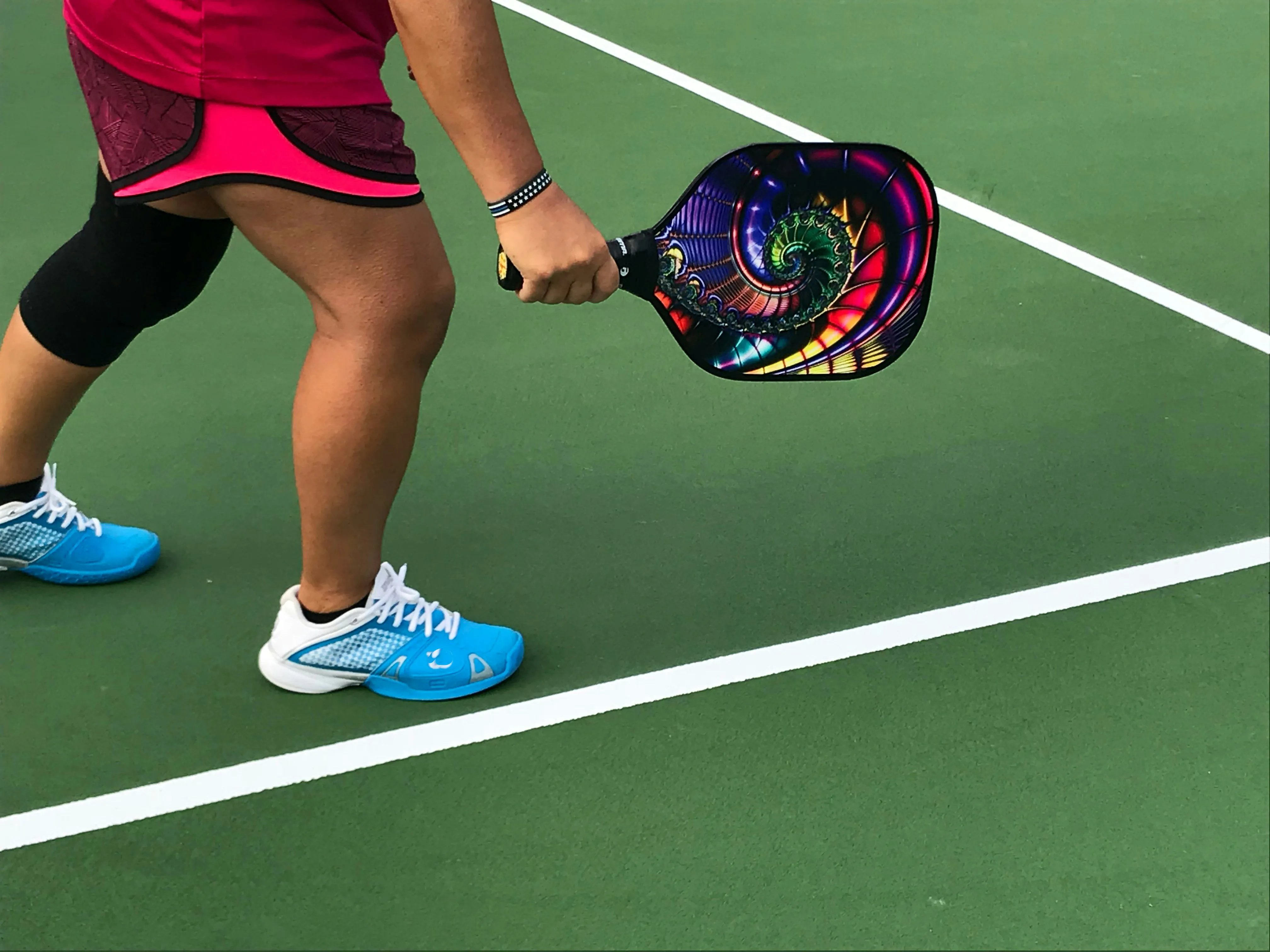 closeup of lower half of woman holding pickleball paddle