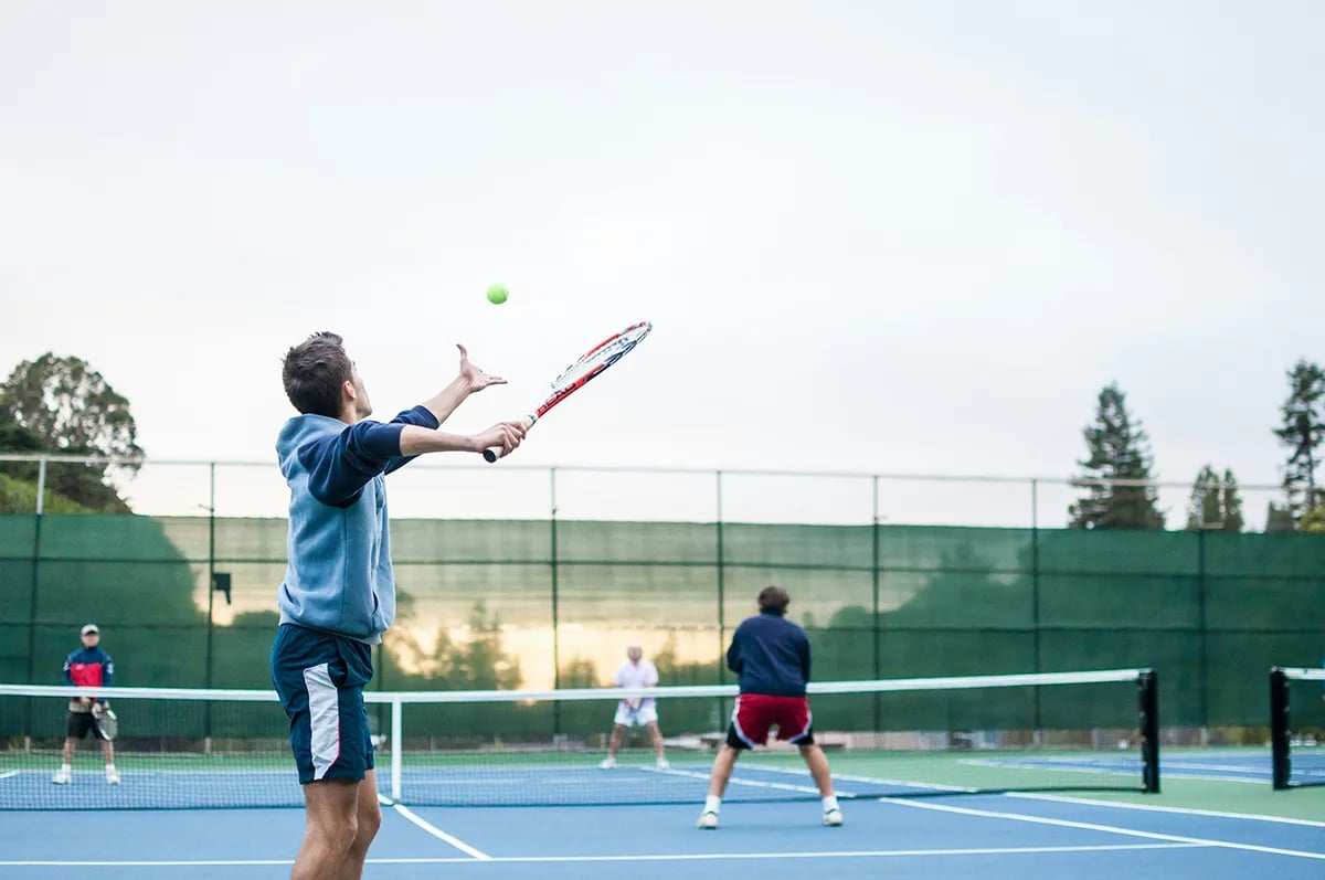 men playing tennis one holding racquet to serve