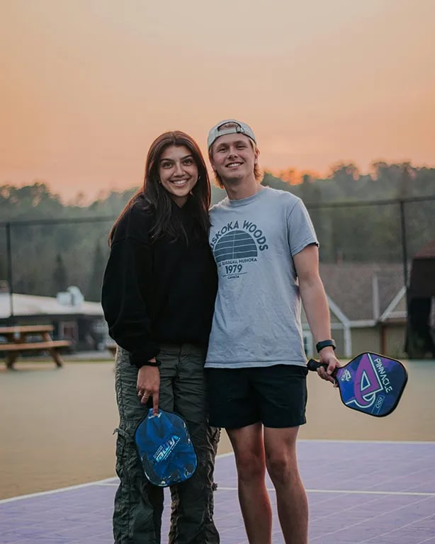 couple on pickleball court with arms around each other and holding paddles