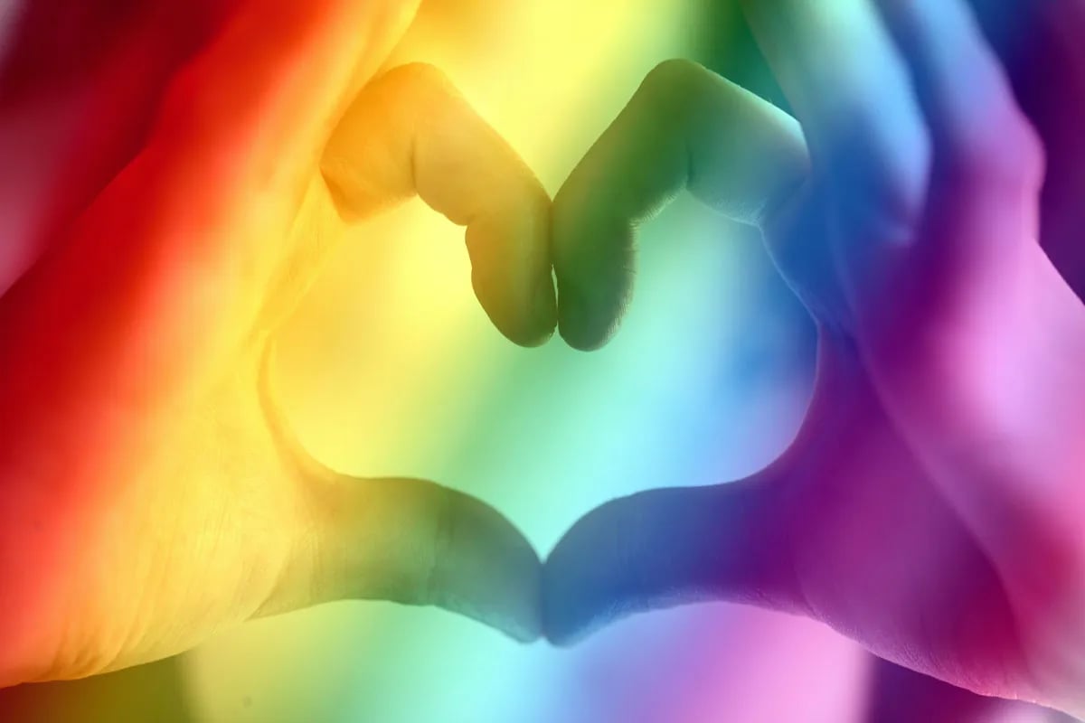 fingers forming heart with a rainbow overlay
