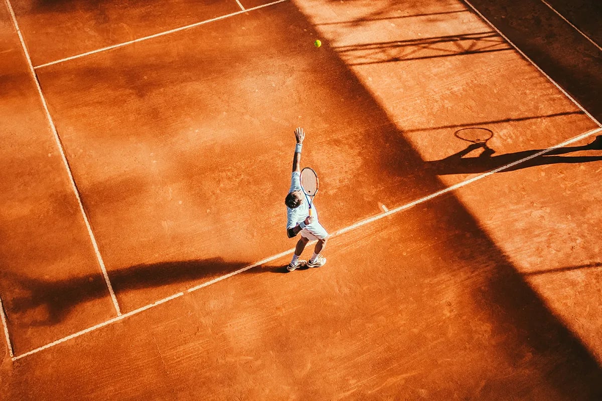 tennis player in middle of a red clay court overview