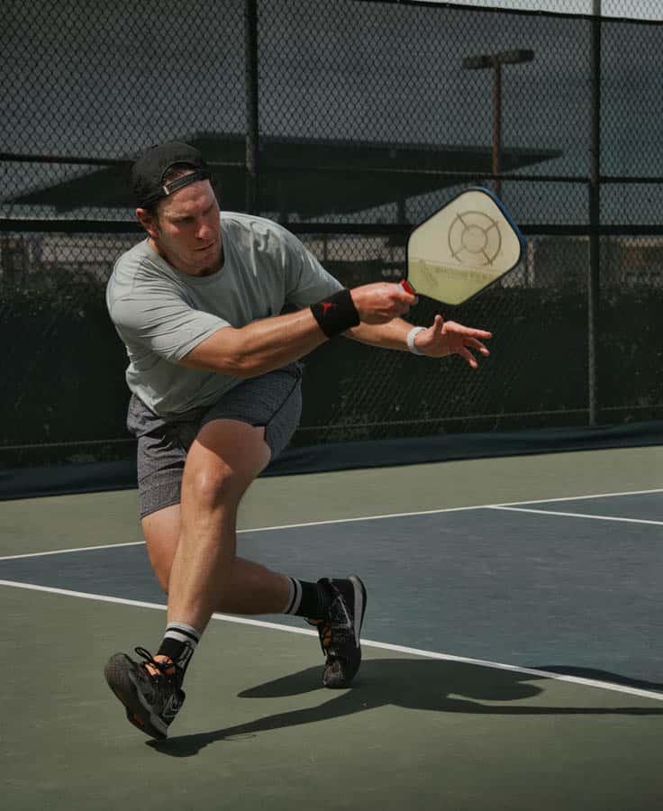 man swinging pickleball paddle on court
