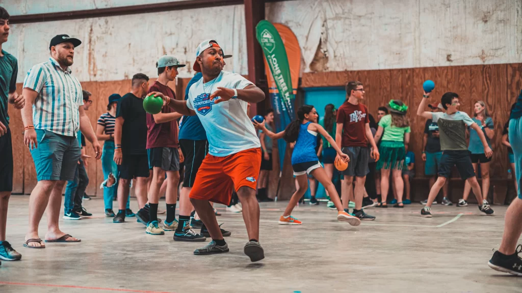 guy with dodgeball in hand winding up getting ready to throw it. he's surrounded by a lot of other dodgeball players.
