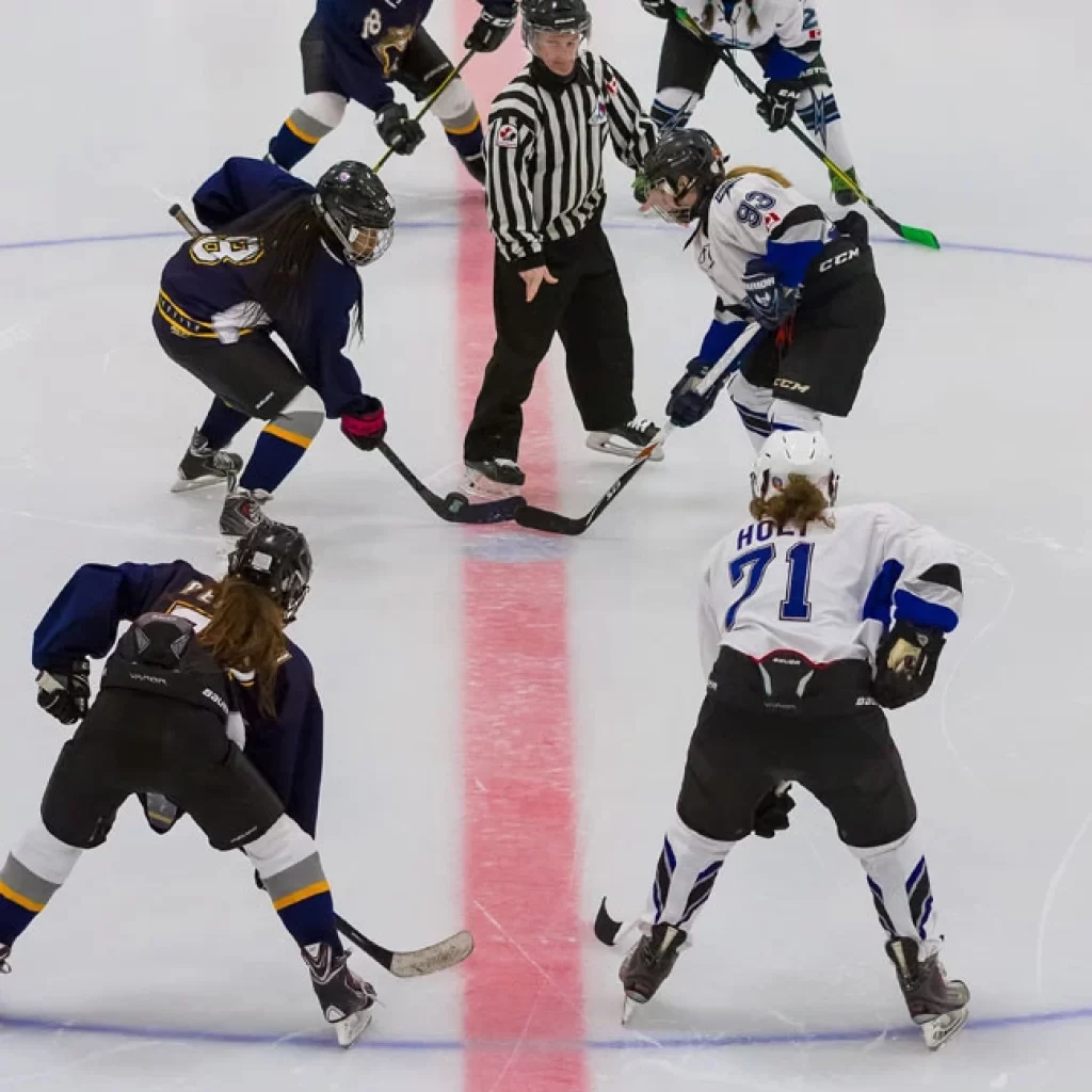 Female hockey players from different teams facing off on the ice
