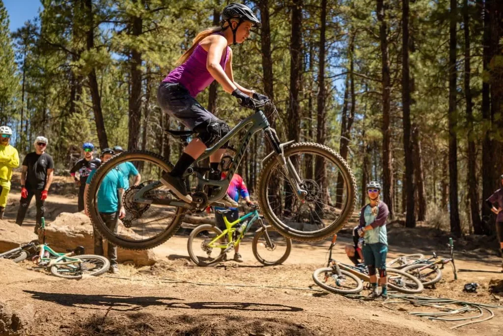 Ninja mountain bike clinic with woman jumping her bike.