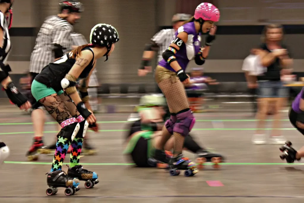 women playing roller derby skating around track. Two women clear in foreground with background blurred.'