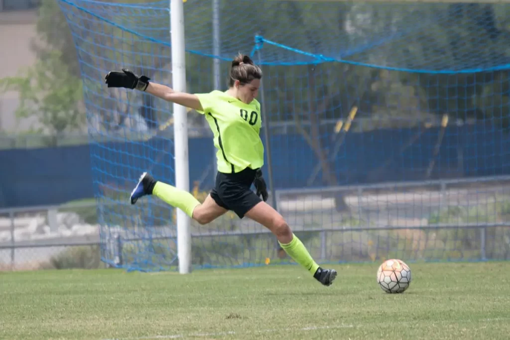 female goalie in yellow jersey kicking ball