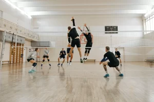 indoor volleyball game with two men jumping at net