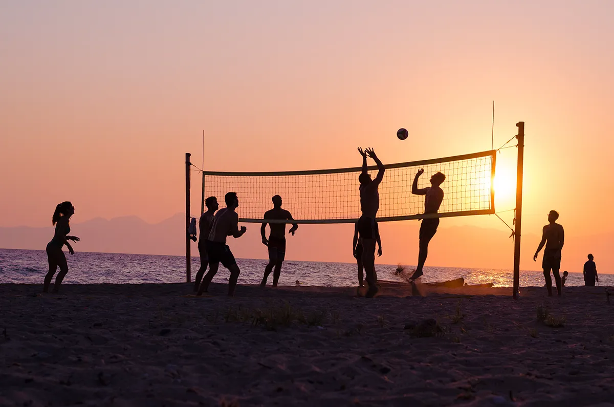 beach volleyball game with silhouettes at sunset