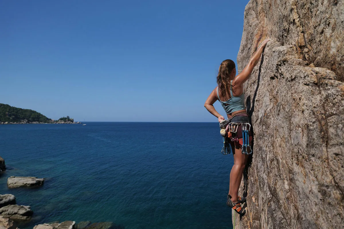 individual sports athlete climbing rock with lake in background