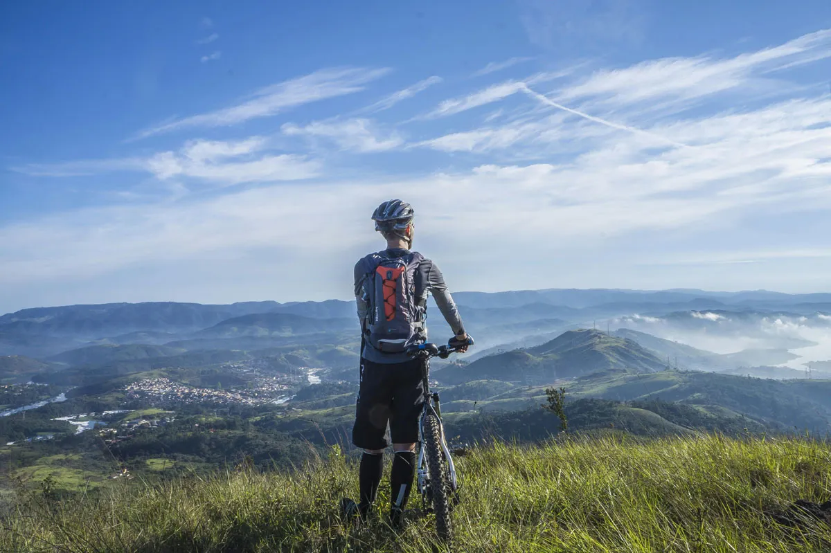 lone mountain biker at top of mountain looking at view below