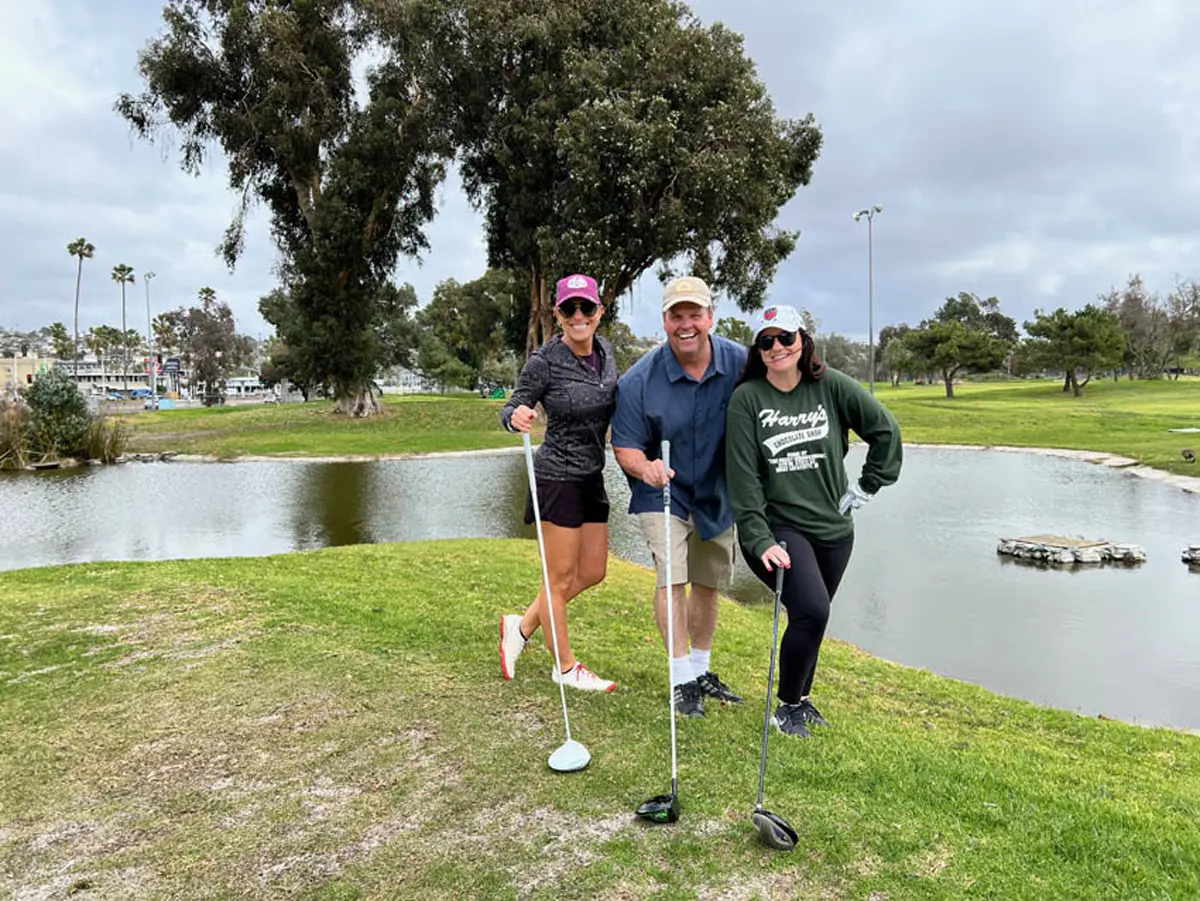 two women and one man posing with golf clubs